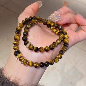 Detailed macro of tiger eye stone beads set with zircon floral accents in golden finish