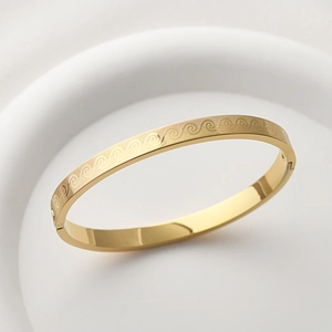 Detailed close-up of golden titanium steel bangle with engraved wave patterns