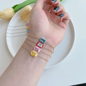 Model wearing stacked s925 silver bracelets with blue, red, pink, and yellow enamel charms
