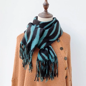 Detail of soft winter scarf featuring black and dark green stripes with fringe tassel ends