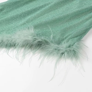 Detail of green sequin fabric with matching luxury ostrich feather fringe trim on the dress