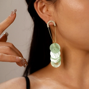 Detail of dangling green geometric drop earrings with sparkling rhinestones on model