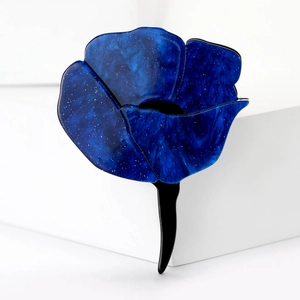Detail of blue acrylic rose brooch with fine glitter texture on a white background