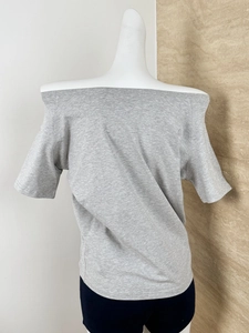 Close-up of a grey off-the-shoulder knit t-shirt with detailed stitching on a mannequin