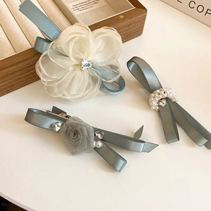 Detail of elegant grey-blue hair clips set with organza flowers, pearls and satin ribbons