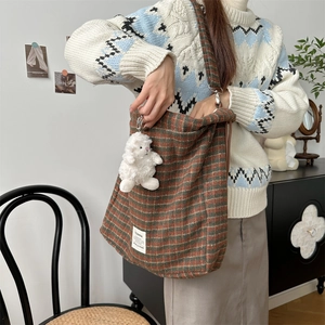 Plaid canvas shoulder bag with plush sheep charm worn by a model in a cozy winter outfit