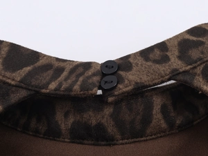 Détail du tissu en daim léopard avec des boutons noirs sur l'encolure de la robe