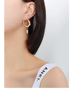 Close-up of asymmetric gold geometric earring with teardrop pearl on female model
