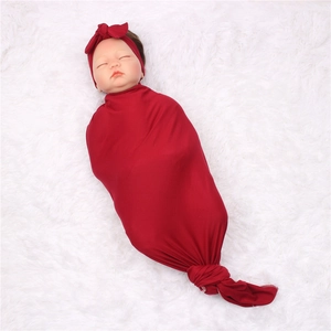Detail view of burgundy newborn swaddle set with a knotted wrap and a matching bow headband