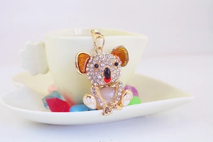 Close-up of golden koala keychain with rhinestones and enamel details in a tea cup