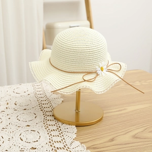 Detail of cream straw hat with white daisy floral decor and delicate lace edge trim