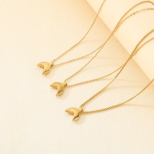 Detailed view of three gold fishtail necklaces with different chain patterns on silk fabric