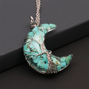 Macro shot of turquoise stone crescent moon pendant with silver wire wrap tree