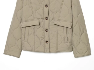 Detailed view of women's khaki quilted jacket with wave stitching and tortoiseshell buttons