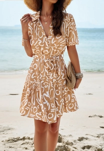 Detail of short sleeve V-neck dress with khaki geometric print and ruffle hem at the beach