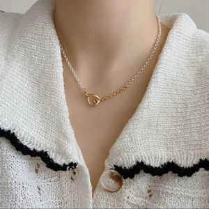 Model wearing two-tone gold and silver chain necklace with irregular ring clasp