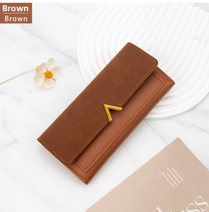 Detailed view of brown long wallet with suede texture and gold V-shaped metal hardware