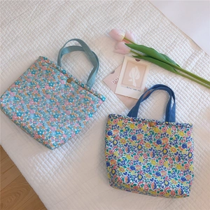 Floral quilted lunch tote bag with thick texture and snap closure in a lifestyle setting