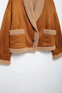 Detail der karamellfarbenen Wildlederjacke mit beigem Lammwollkragen und Knöpfen