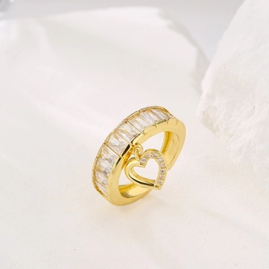 Golden heart pendant ring with square zirconia stones on a white stone background