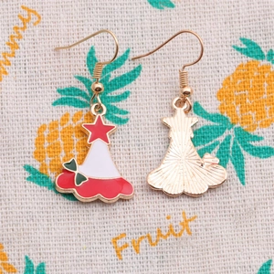 Détail de boucles d'oreilles chapeau de Noël en émail avec étoile rouge et nœud vert