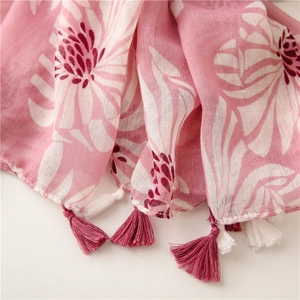 Gros plan d'une écharpe fleurie rose en lin avec des détails de franges en coton