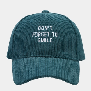 Close-up of white letter embroidery on dark green corduroy fabric baseball cap