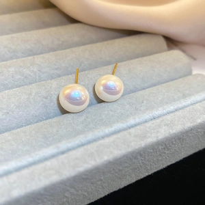 Macro shot of iridescent mermaid pearls on gold posts resting in a gray velvet jewelry box