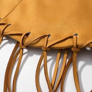 Close-up of ginger suede fabric featuring metallic eyelets and tassel fringe detailing