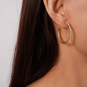 Close-up of elegant gold hoop earrings with pavé diamonds worn by a model