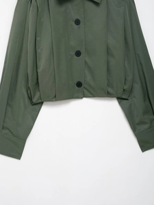 Detail der dunkelgrünen Herbstjacke mit drei schwarzen Knöpfen und gefaltetem Ärmel