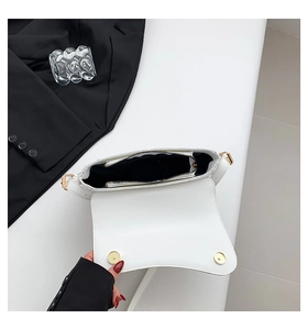 Detail view of the white flap bag's interior compartment with golden magnetic buckles