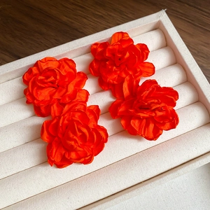 Elegant orange fabric flower earrings and brooch set with satin luster on a jewelry tray