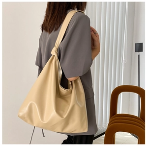 Beige oversized tote bag featuring stylish knotted straps on model's shoulder for daily use