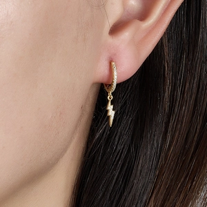 Macro shot of a gold-plated lightning bolt earring with pavé-set cubic zirconia stones