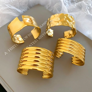 Detailed view of four golden stainless steel bangles with textured and polished finishes