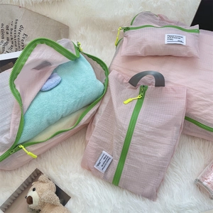 Detail view of pink waterproof grid travel organizers with green zippers on plush rug