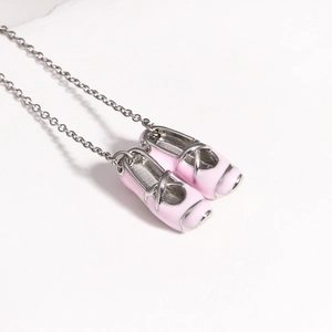 Detailed macro view of delicate pink enamel ballet shoe pendants on a silver chain