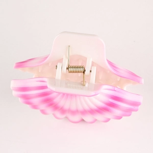 Close-up of pink shell hair clip with metal spring and smooth gradient texture