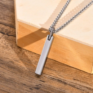 Close-up of a silver tungsten steel rectangular bar pendant on a rustic wood surface