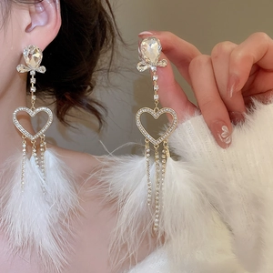Detail of silver needle earrings with crystal heart, long tassels and white feathers
