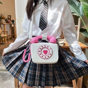 White vintage telephone shaped crossbody bag with pink accents worn by a model
