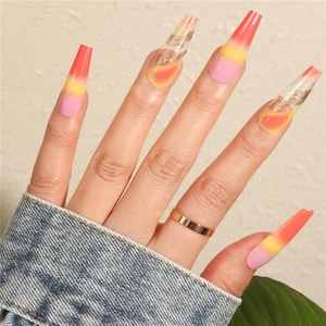 Close-up of long coffin press-on nails with pink orange gradient and gold foil accents