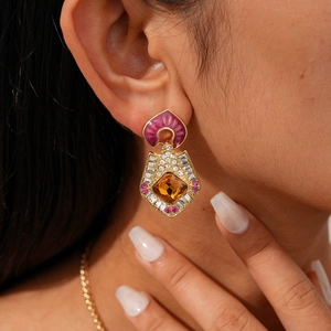 Gros plan sur boucle d'oreille vintage dorée avec pierre ambre et gemmes roses