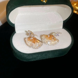 Detail of ginkgo leaf stud earrings with champagne crystals on a green velvet box