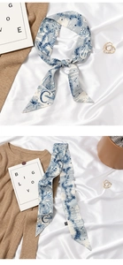 Close-up of blue and white silk twilly scarf with letter C and Toile de Jouy pattern