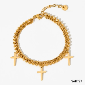 Détail du bracelet double couche en acier inoxydable doré avec trois breloques en croix