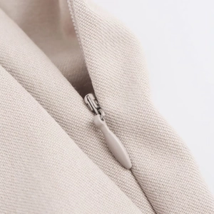 Macro detail of hidden zipper closure and high-density beige fabric texture on trousers