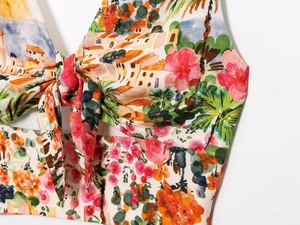 Detail of colorful floral landscape print crop top with front tie knot and fabric texture