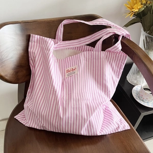Borsa tote in tela a righe bianche e rosa in stile francese su sedia di legno rustica